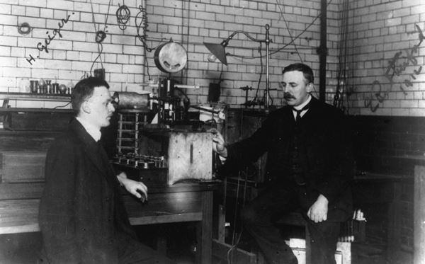 1909년 영국 맨체스터 대학 실험실의 러더포드(오른쪽)와 그의 조수 한스 가이거. 실험기구는 알파입자의 금박 충돌을 관찰하는 섬광계수기로  '러더포드 원자모형(태양계 모형)'을 발견하는 데 공헌했다. 출처: BBC