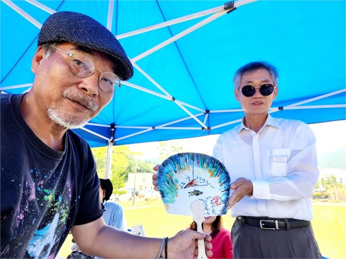 동양화가인 몽피 김경학(왼쪽) 선생이 즉석에서 쥘부채에 그림을 그려 선물하고 있다. 사진=지리산문화예술학교 제공